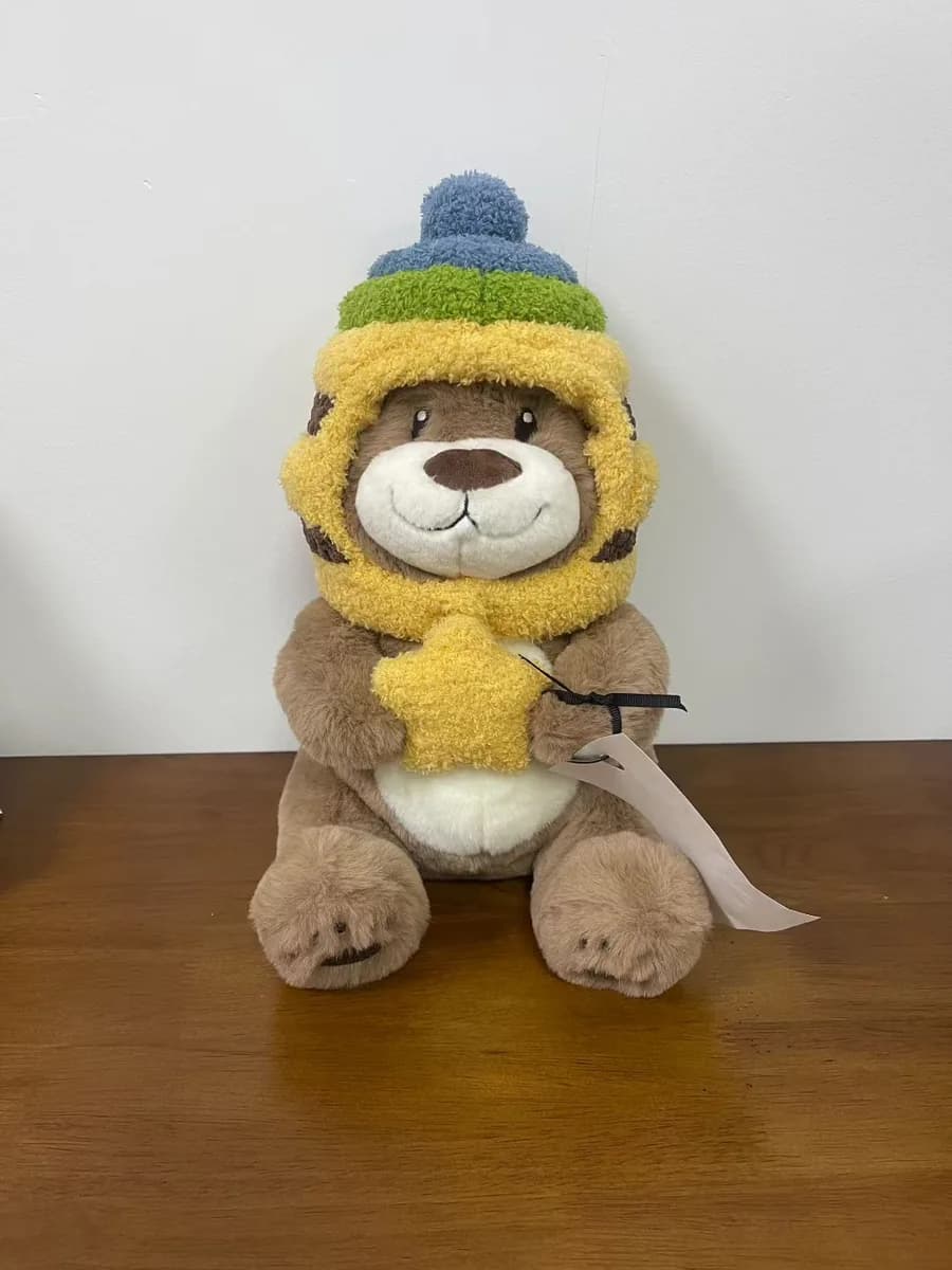 Bear plush toy wearing a knitted beanie and scarf