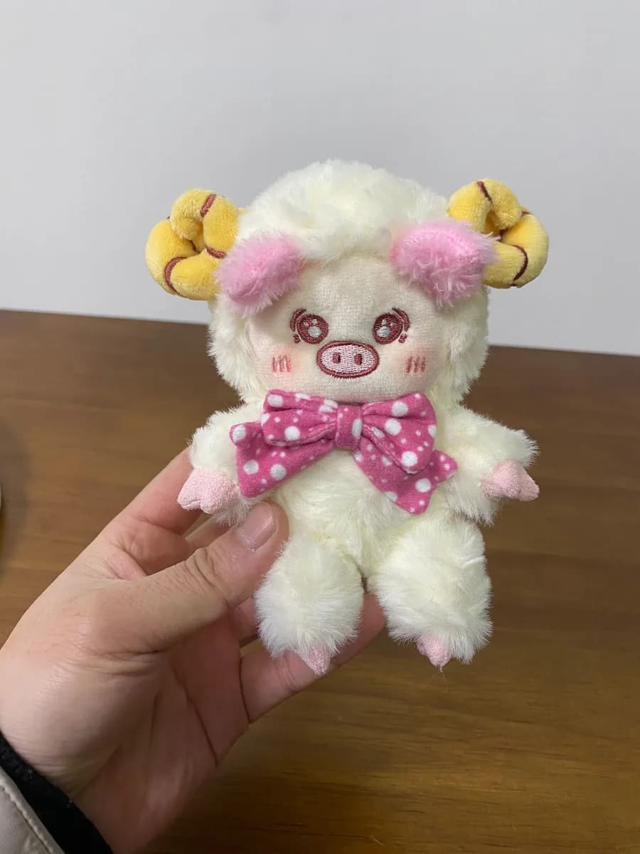 White sheep plush toy with curly fur and a pink bow