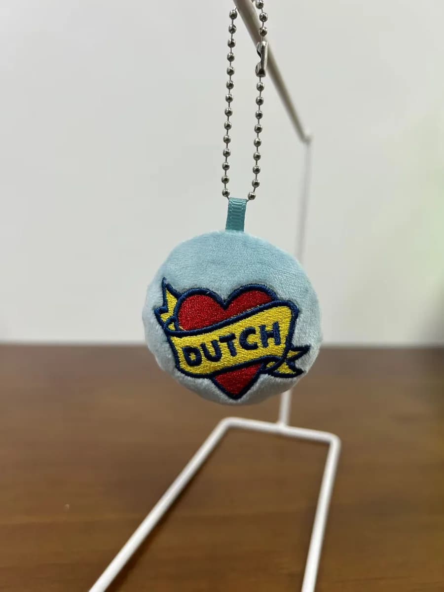Round plush badge charm with woven label detail