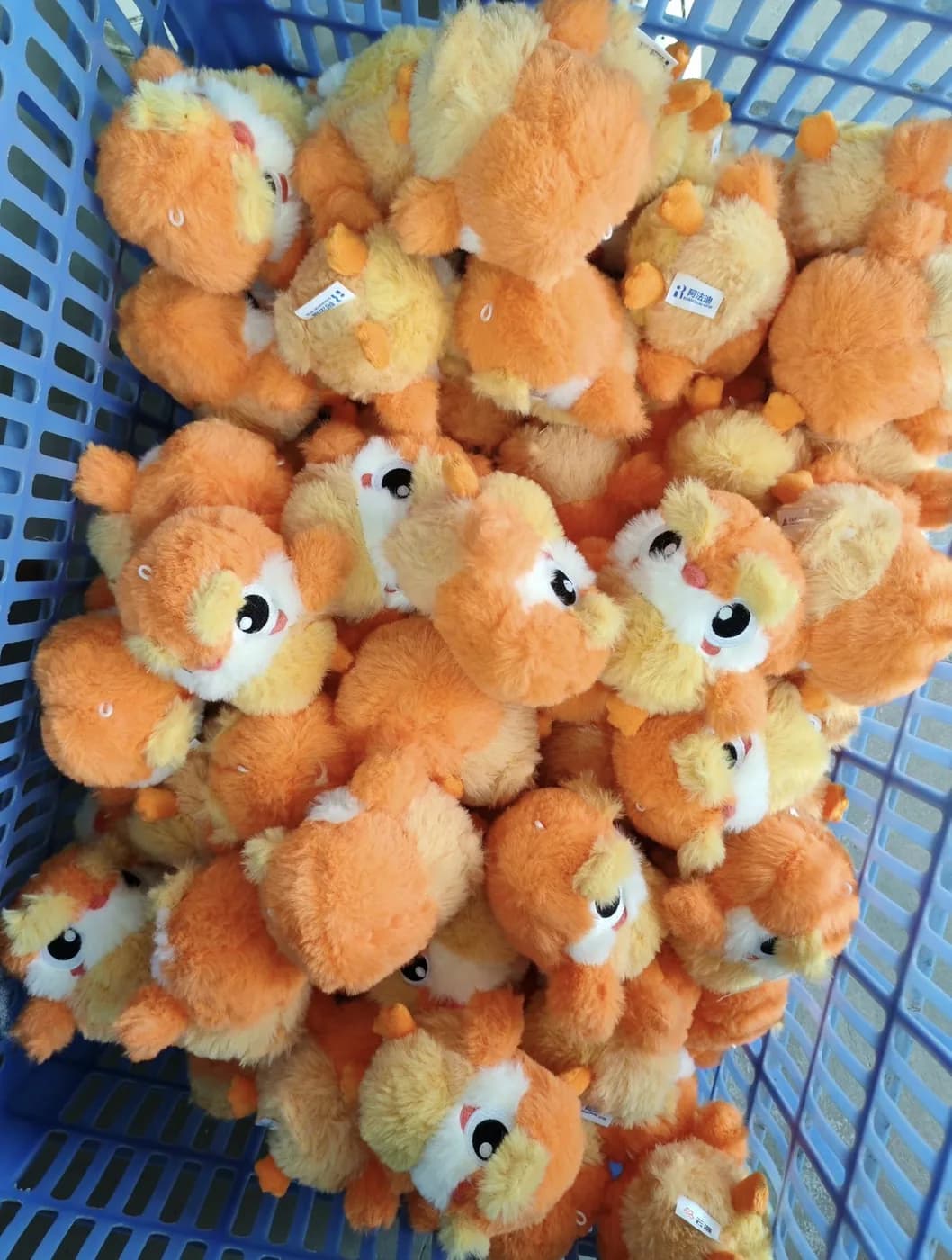Bulk run of orange plush toys in a production crate