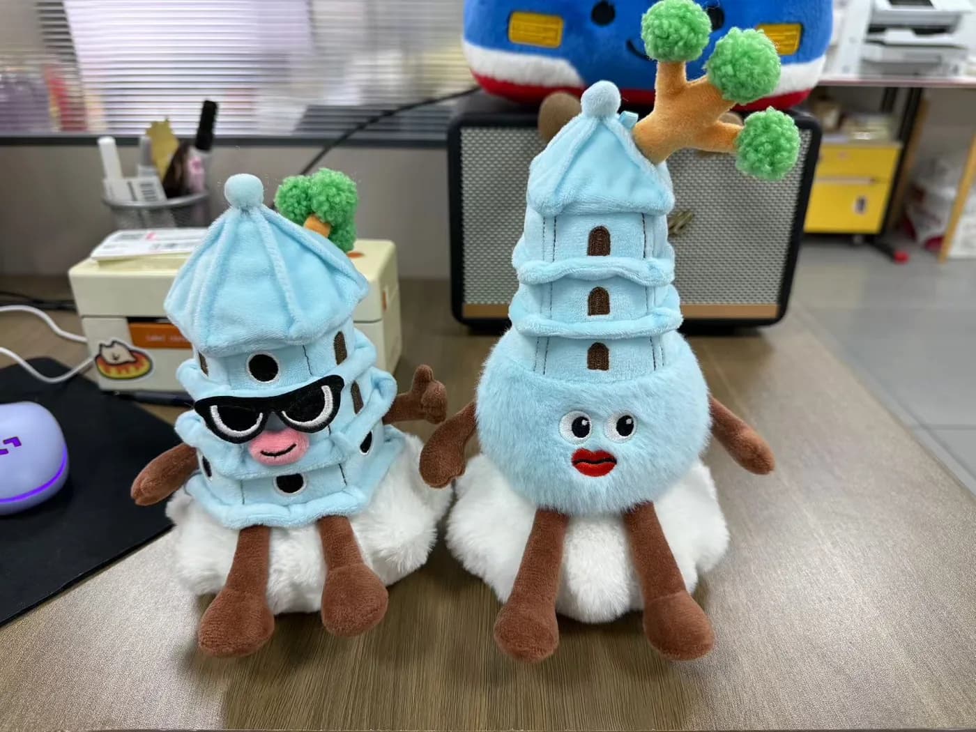 Two matching landmark plush souvenirs on a desk